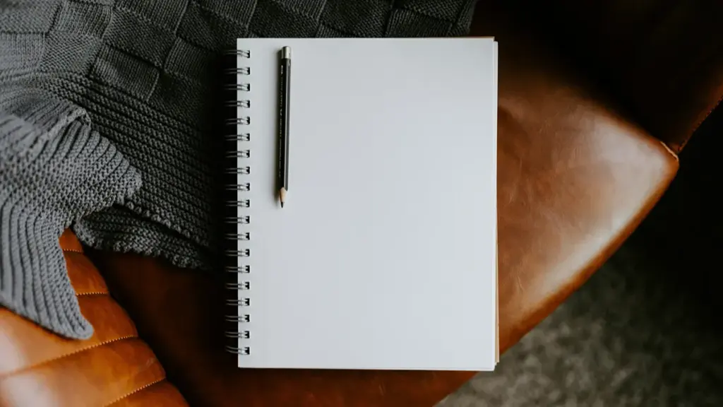 Blank spiral sketchbook and pencil on a brown leather chair