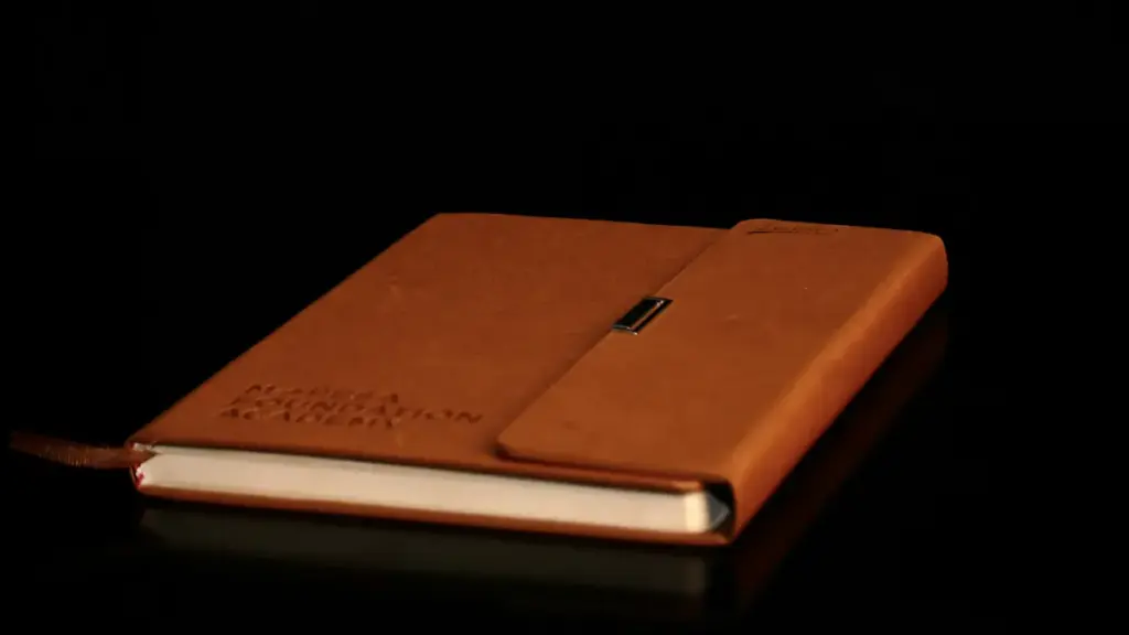 Closed brown leather journal resting on a dark reflective surface