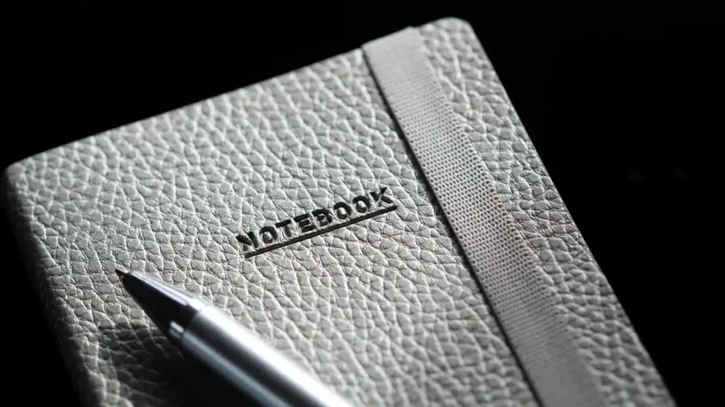 Silver ballpoint pen resting on a grey textured leather notebook