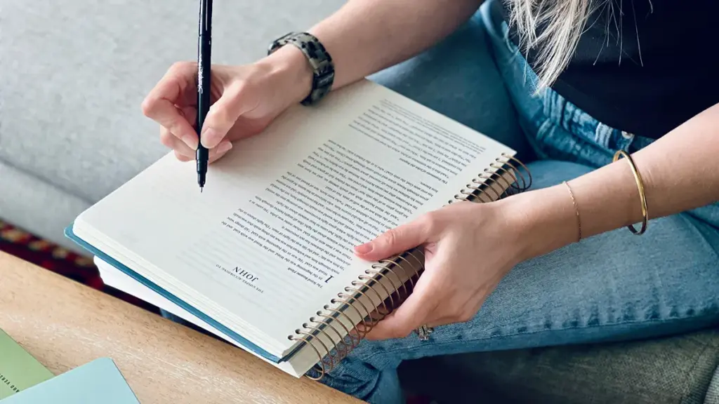a woman is writing on the sipral notebook