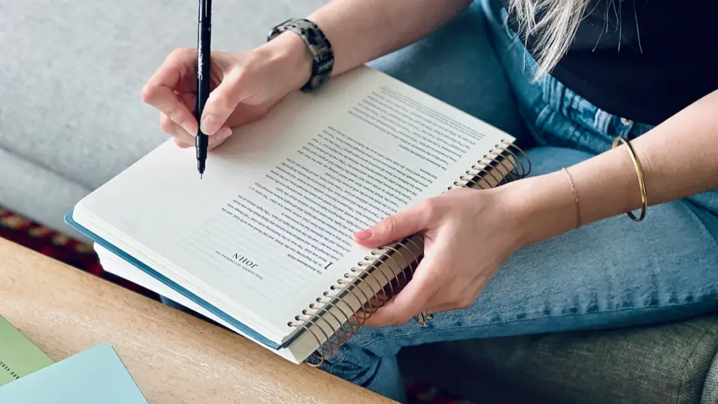 A woman writing notes in a wire o notebook with a black pen