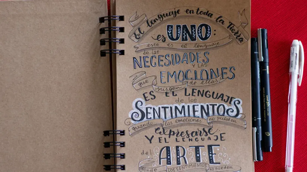 An open spiral notebook with handwritten Spanish calligraphy and pens