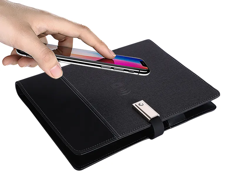 A hand placing a smartphone onto a black wireless charging wallet with a magnetic clasp.