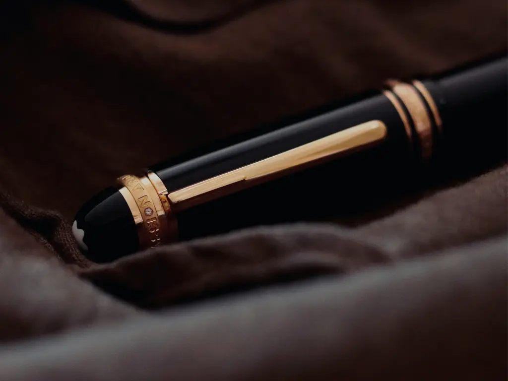 Close-up of a luxurious black Montblanc fountain pen with gold trim resting on soft brown fabric