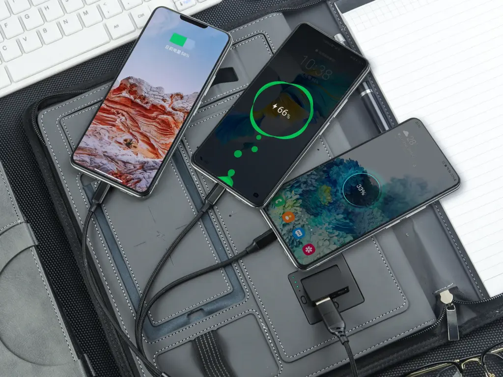 Grey wireless charging notebook with three smartphones charging simultaneously.