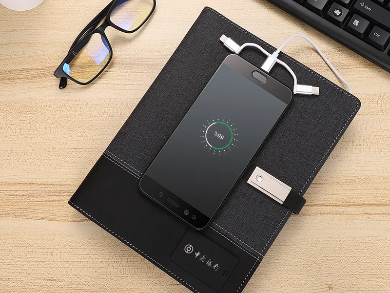 Black fabric phone wallet case with wireless charging function, showing 59% battery on smartphone screen, placed on wooden desk with glasses and keyboard nearby