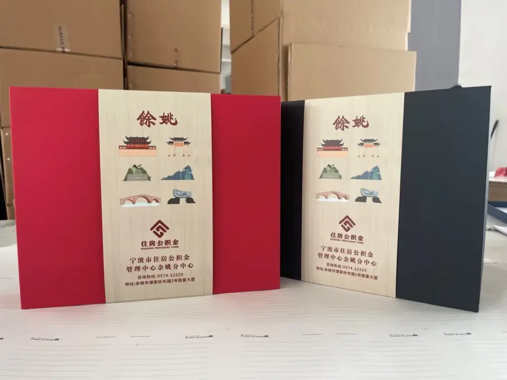 Two color folder designs featuring Yuyao housing provident fund branding with traditional Chinese architecture, bridge, and landscape illustrations on textured beige panels
